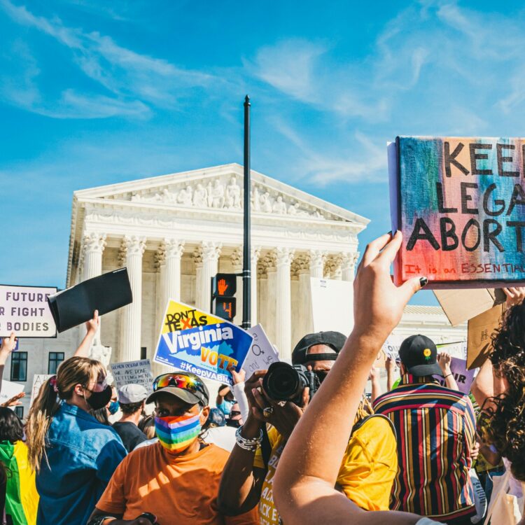 Protestors in front of the Capitol featuring a sign saying keep legal abortion