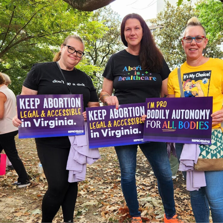 Three female protesters holding keep abortion legal and accessible signs
