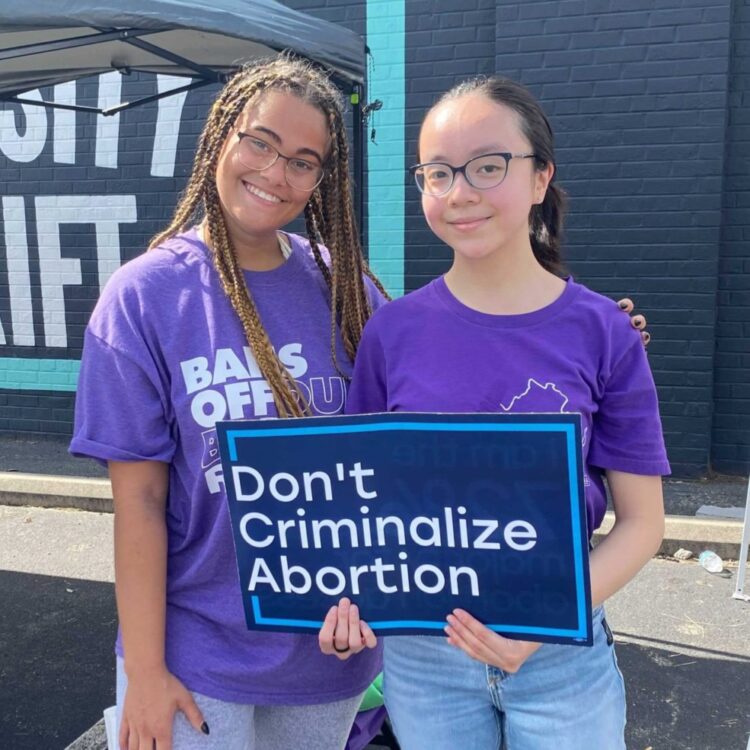 two student fellows holding a sign that says &quot;don&#039;t criminalize abortion&quot;